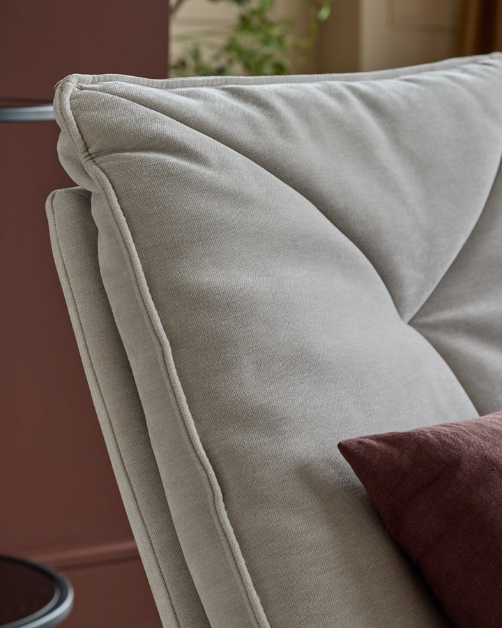 Zia Swivel Chair in natural grey fabric, close-up of curved armrest and seat detail.