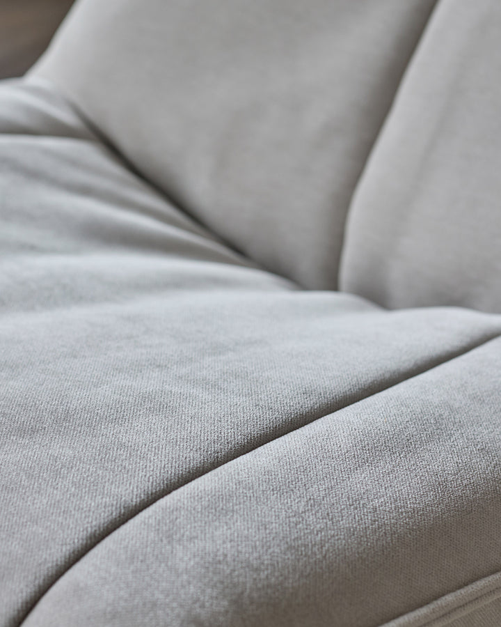 Close-up of natural grey fabric on Zia swivel chair, showing soft upholstery texture and curved seating detail.
