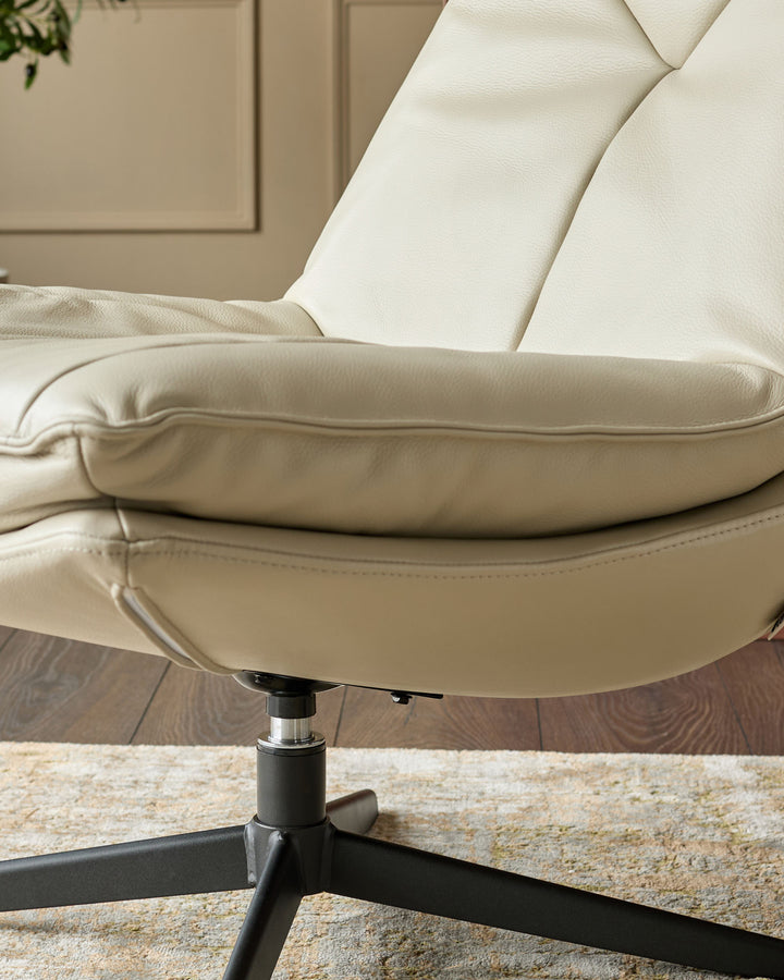 Cream leather swivel chair with padded armrests and high backrest, featuring a black metal base on a neutral area rug.