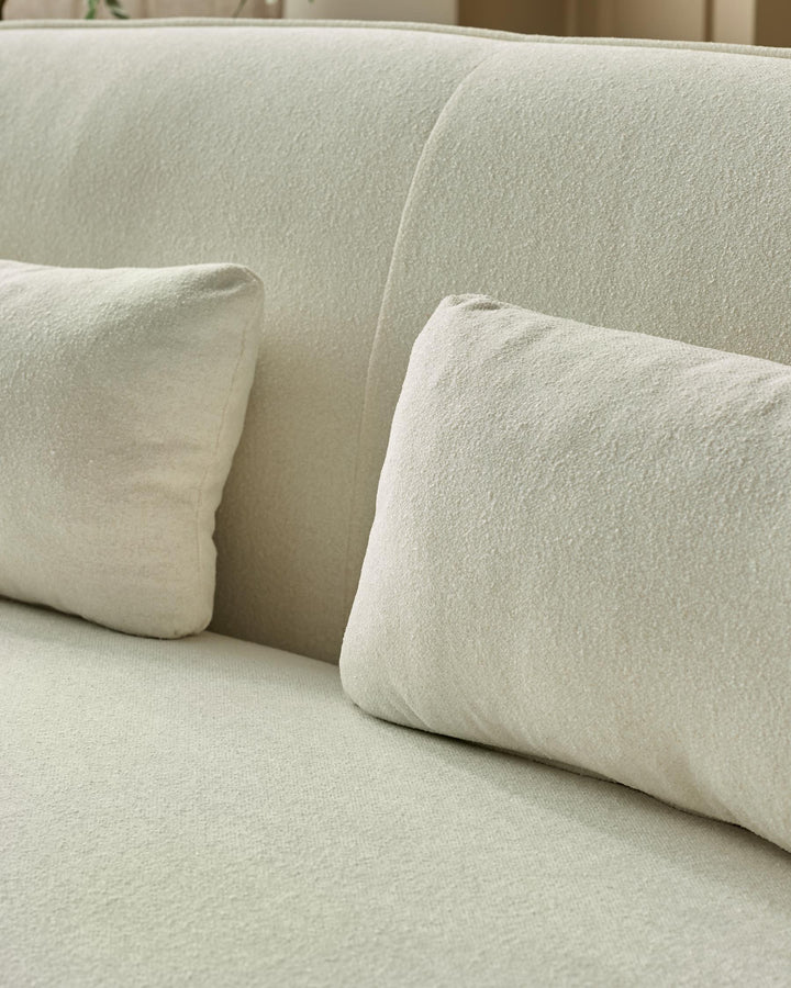 Close-up of a stylish, textured, off-white sofa with plump matching cushions. Cosy and inviting.