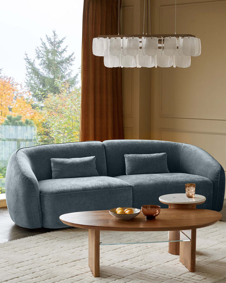 Stylish living room with a plush grey sofa, wooden coffee table, marble side table and statement lighting.