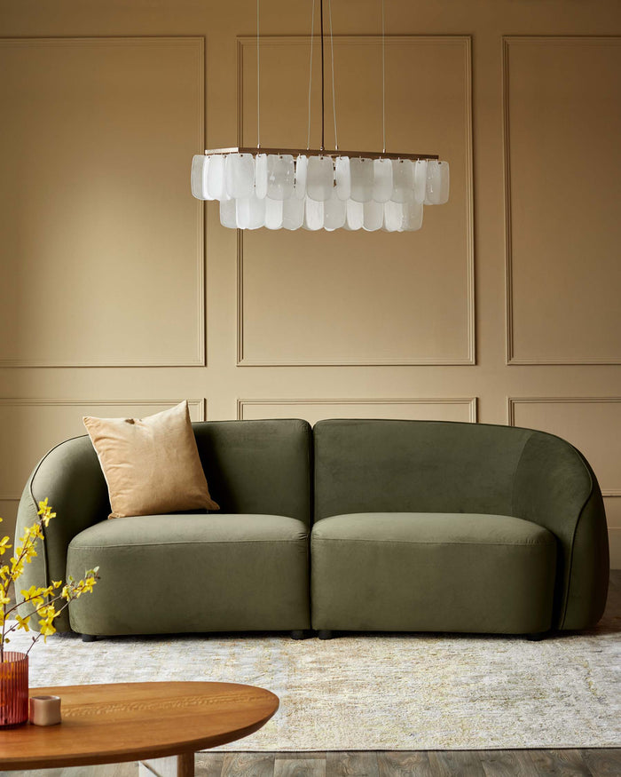 Stylish green sofa with a beige cushion beneath a modern chandelier, creating an elegant and inviting living space.