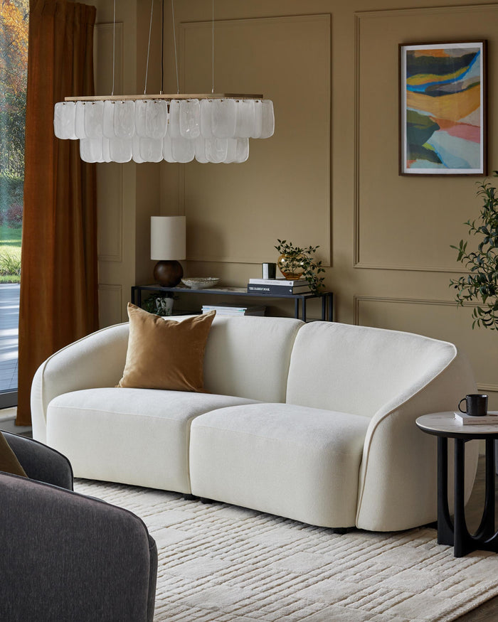 A modern living room with a white sofa, a dark grey armchair, and a statement chandelier.