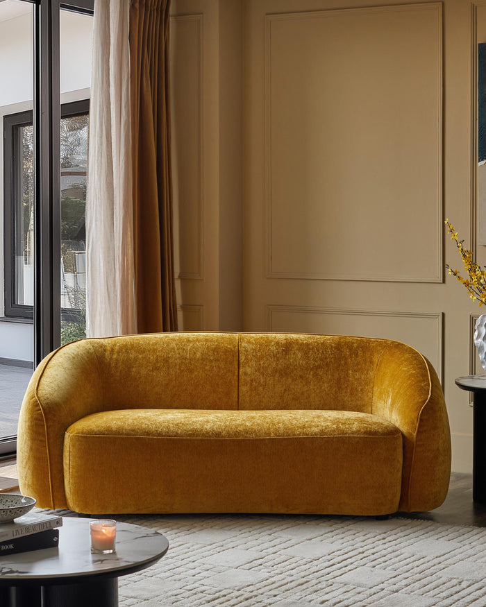 A plush, gold velvet sofa takes centre stage, complemented by stylish coffee tables in a neutral and sophisticated living room.