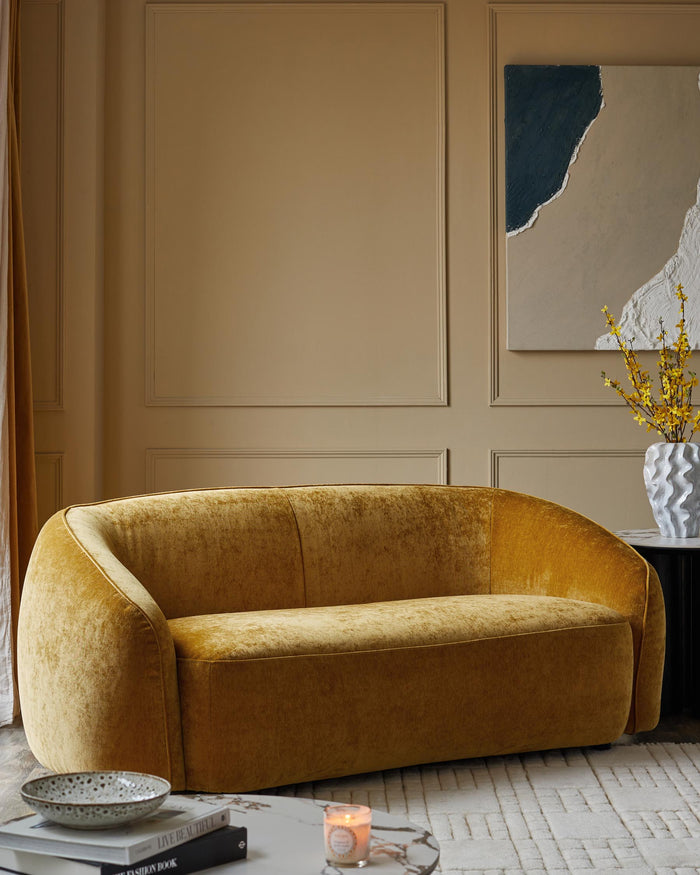 A stylish mustard velvet sofa, complemented by accessories and a neutral backdrop.