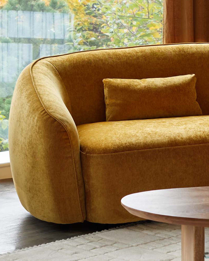 Stylish mustard velvet sofa with a wooden coffee table, creating a cosy and modern living room vibe.