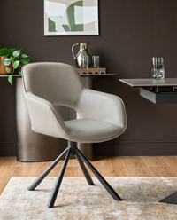 Light grey leather swivel dining armchair with curved back and black metal tripod base, shown in room setting.