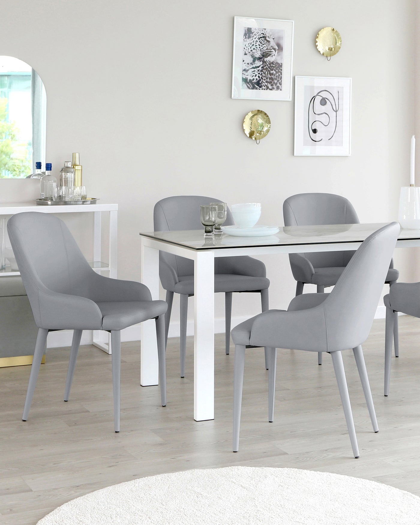 Modern dining set featuring a rectangular white table with a minimalist design and four matching grey upholstered chairs with sleek legs.