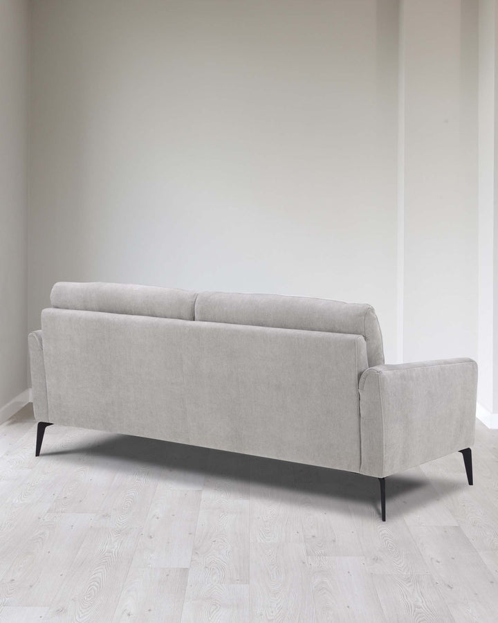 Modern three-seater sofa with a minimalist design featuring light grey upholstery and tapered black wooden legs.