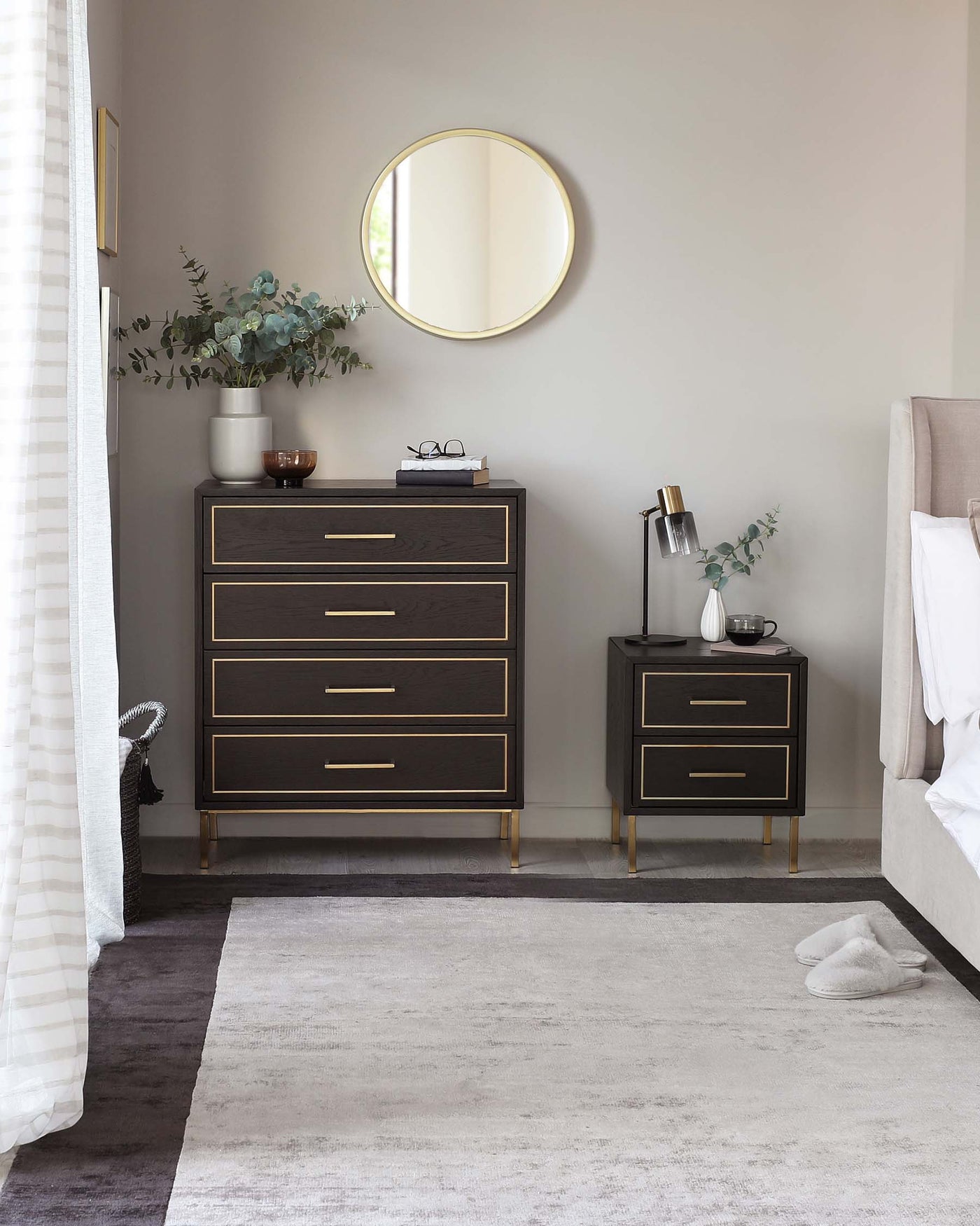 Elegant bedroom furniture set with a dark wood finish and gold metal accents. The collection includes a tall five-drawer dresser and a two-drawer nightstand, both featuring sleek handles and raised on tapered legs. A simple, yet sophisticated design ideal for a modern home interior.