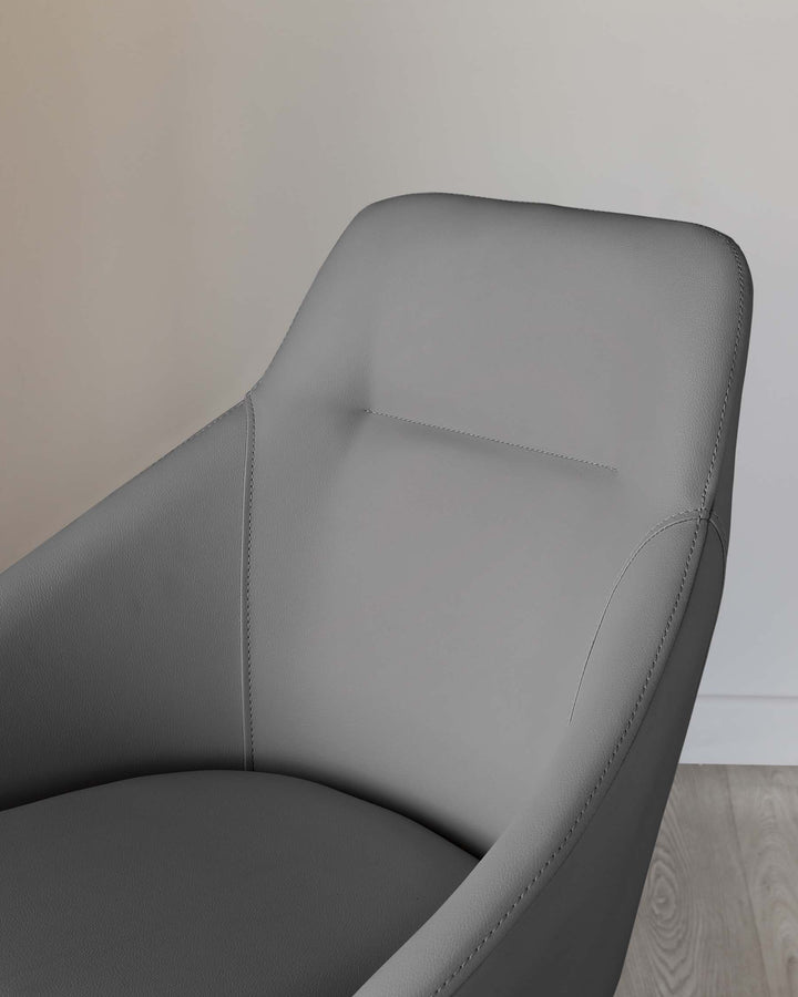 Modern grey upholstered armchair with clean lines and elegant stitching detail, positioned on a wooden floor against a neutral wall backdrop.