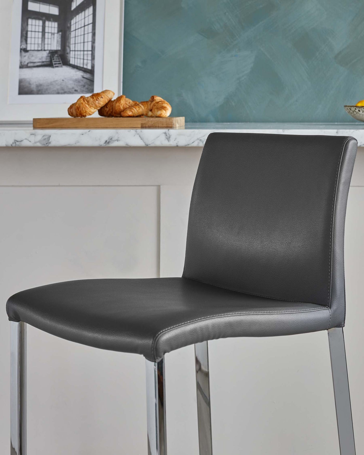 Modern black leather dining chair with a streamlined chrome frame and minimalist design.