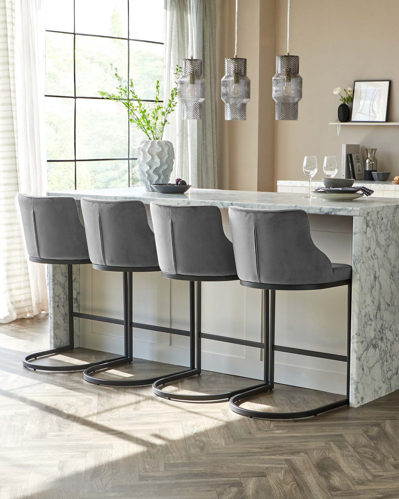 Elegant grey upholstered bar stools with backrests and sleek black metal legs, paired with a marble kitchen island.