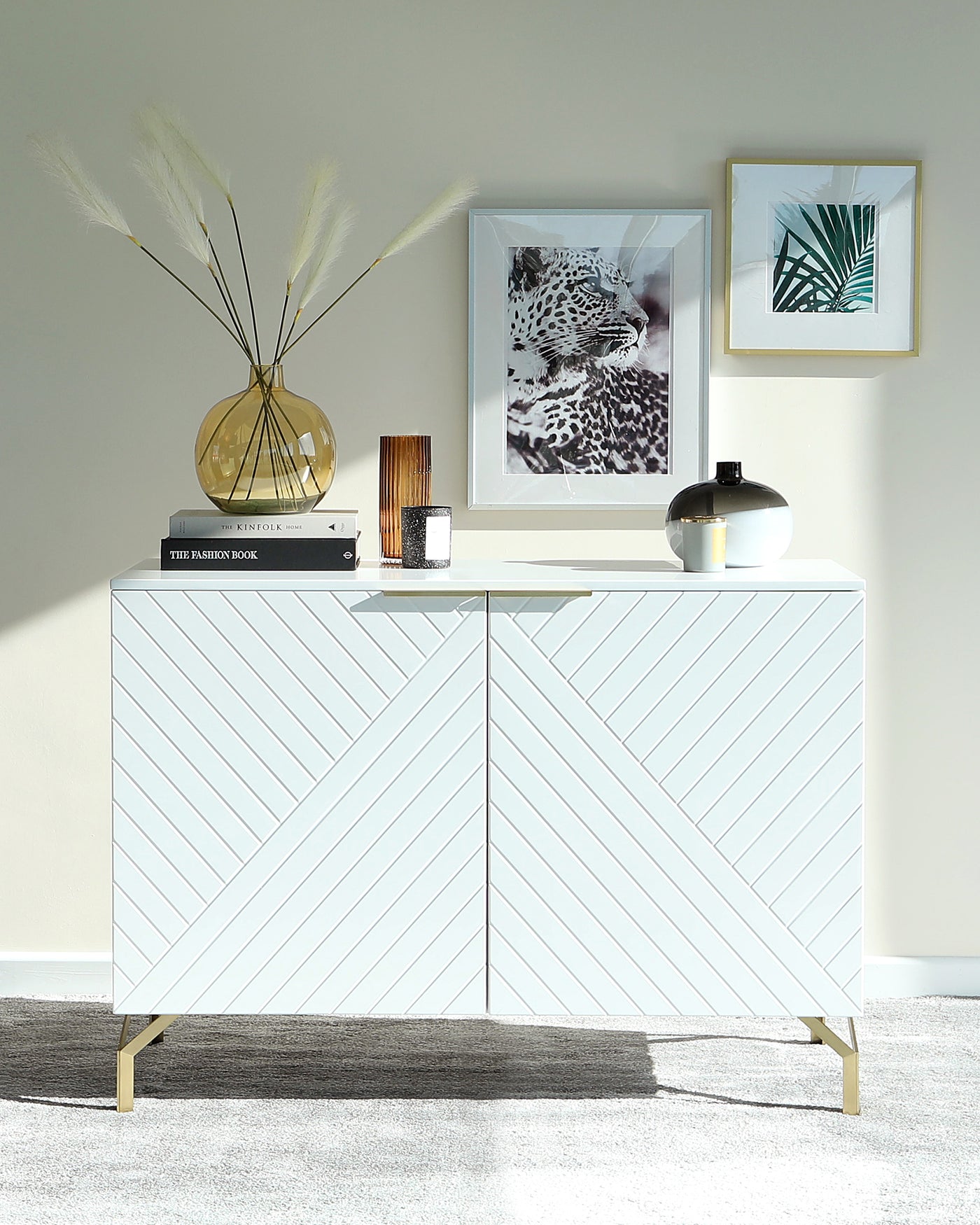 A modern white sideboard cabinet with a chevron pattern and brass legs.