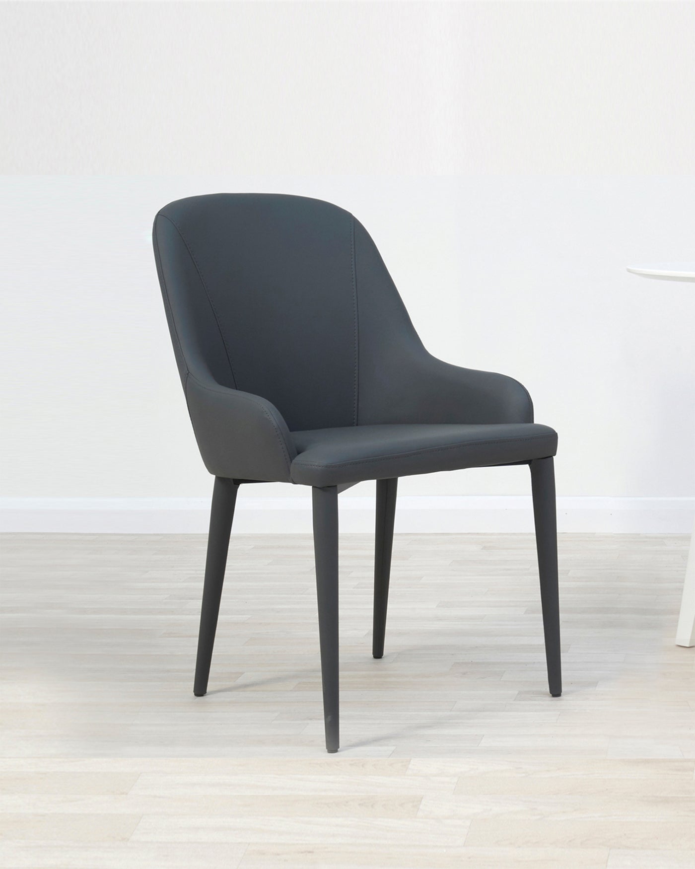 Modern charcoal grey upholstered dining chair with a curved backrest and four straight, black wooden legs.