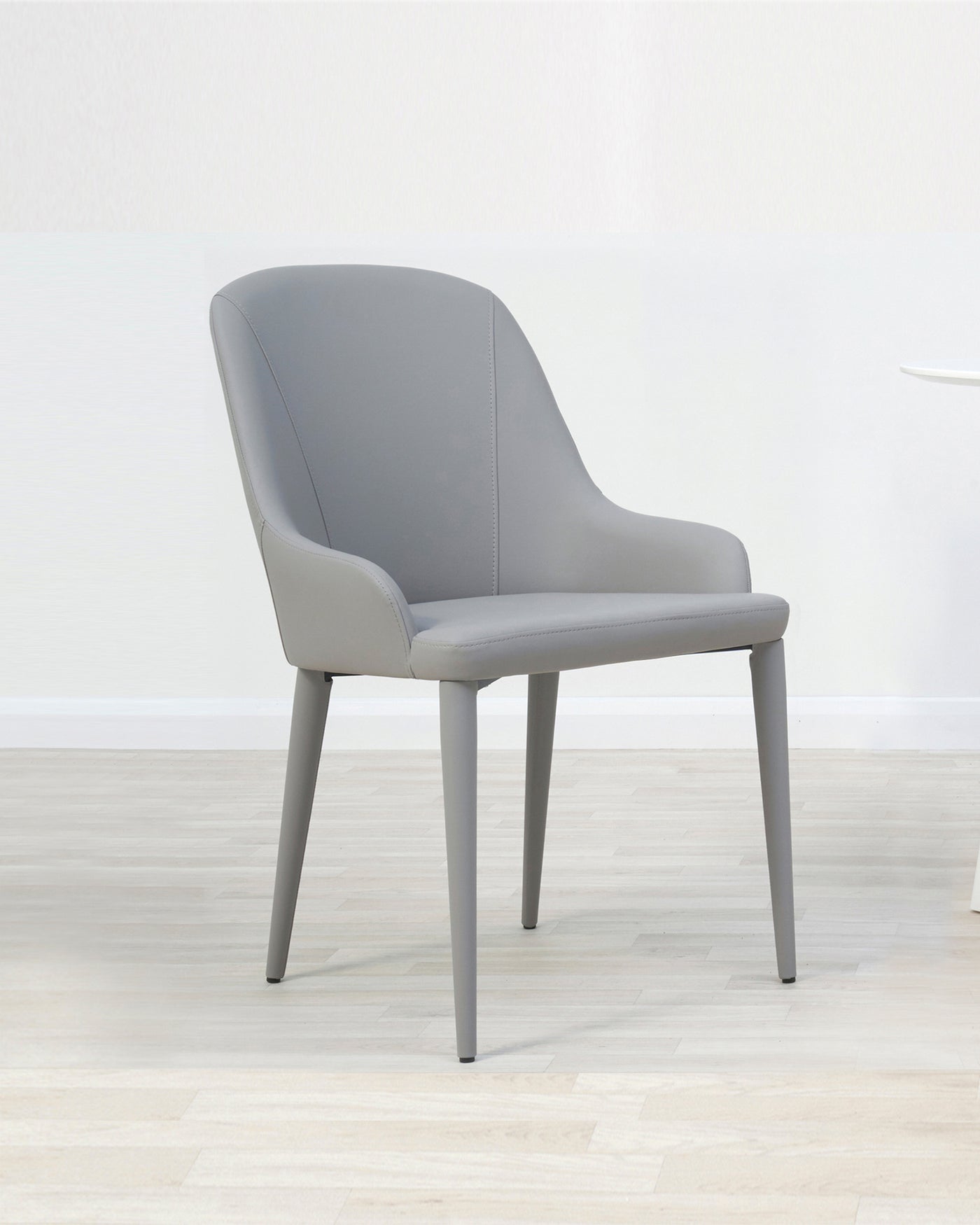Modern grey dining chair with upholstered seat and backrest, featuring a curved silhouette and streamlined metal legs.