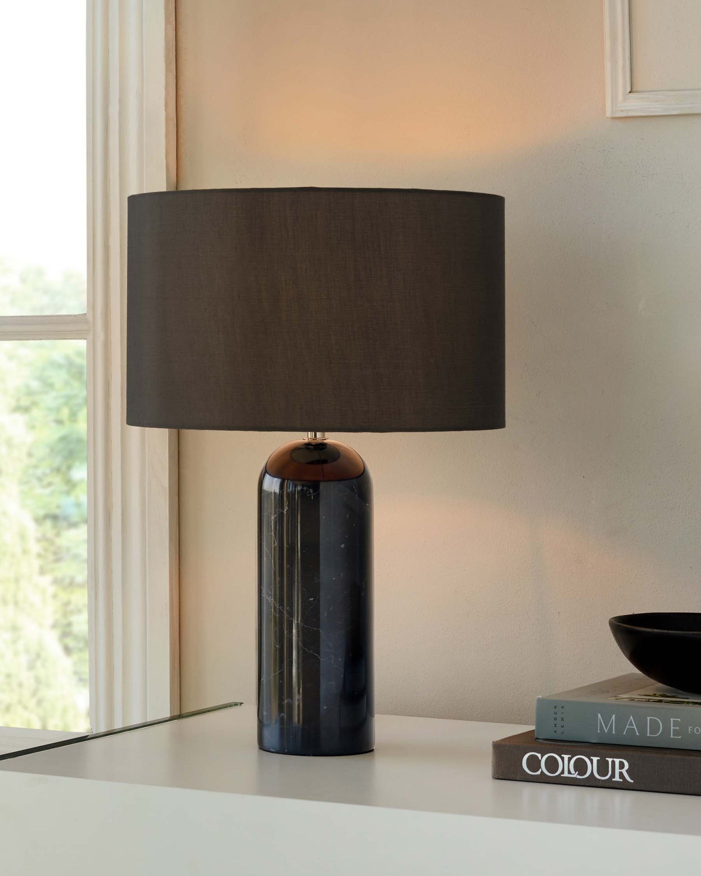 Modern table lamp with a cylindrical navy blue marble base and a wide dark grey lampshade.