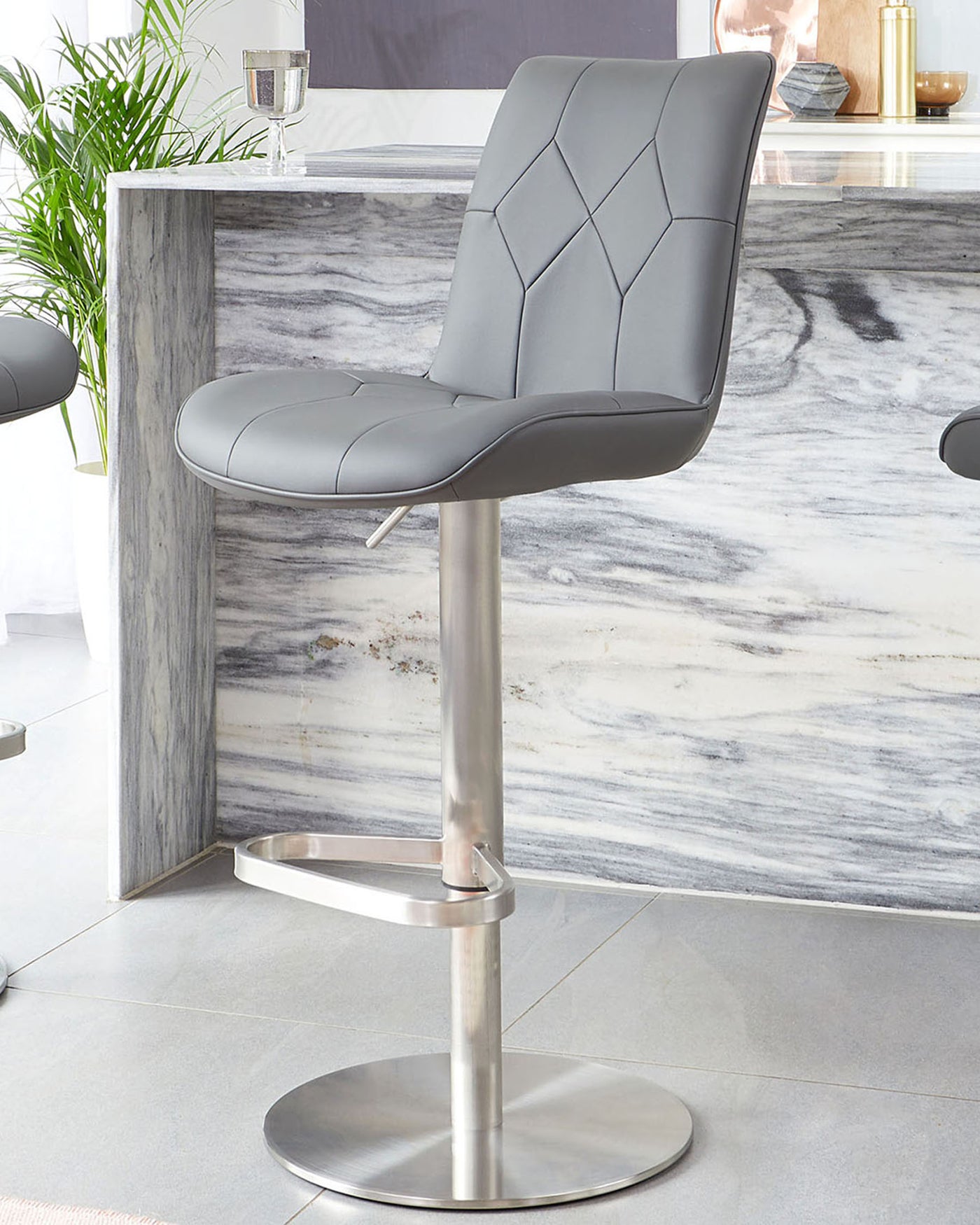 Modern grey faux leather bar stool with a tufted backrest design, chrome pedestal base, and built-in footrest.