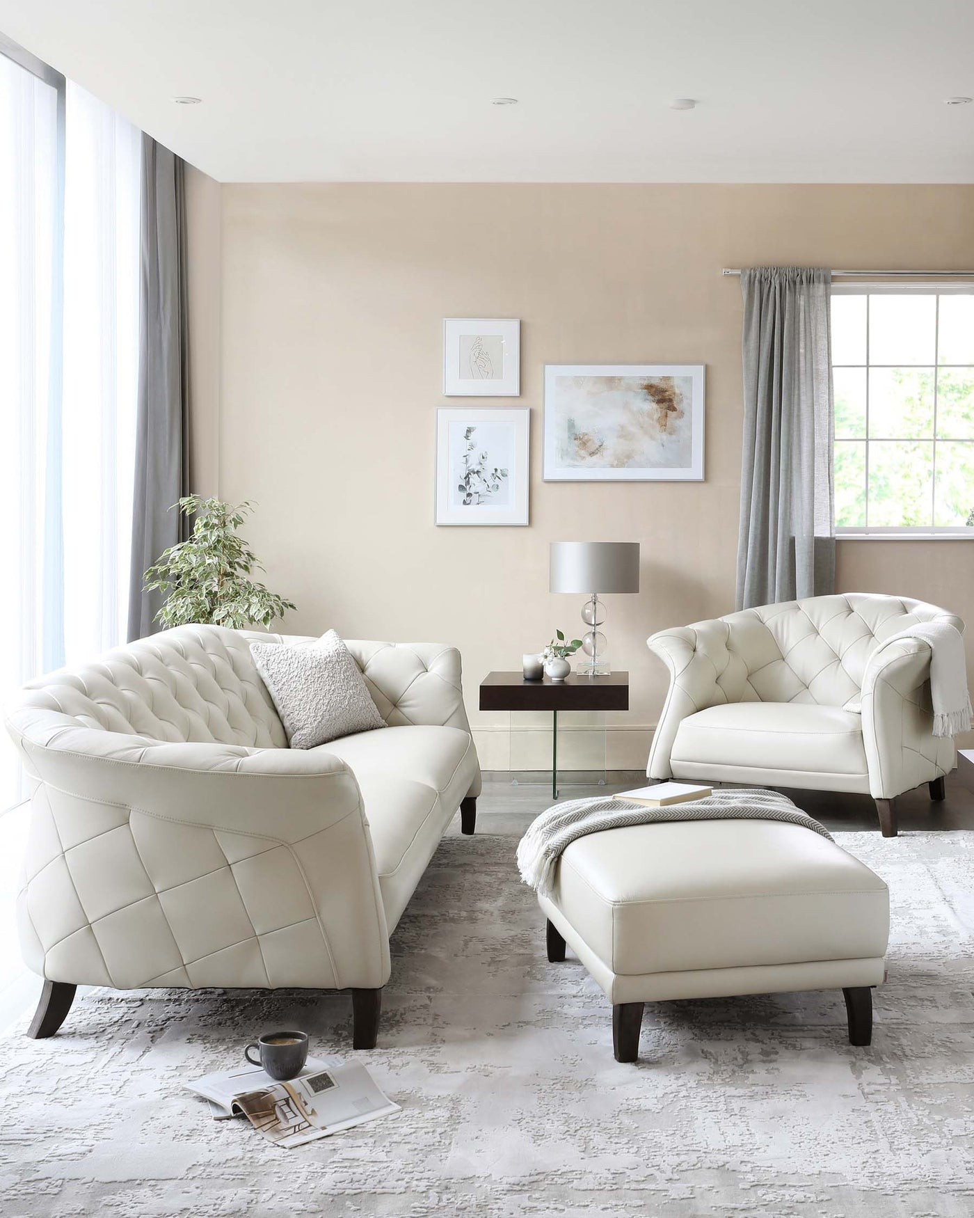 Elegant and contemporary living room set featuring a white tufted leather sofa with matching armchair and ottoman. The sofa and armchair have curved outlines and are adorned with diamond-patterned stitching, resting on dark wooden legs. A sleek, wooden side table with a small lamp complement the arrangement, placed on a textured light grey area rug.