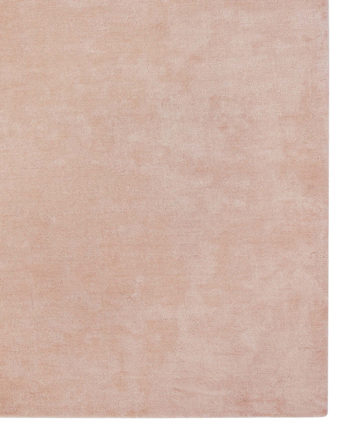No furniture is visible; the image displays a solid blush pink-coloured rug with a subtle textured finish.