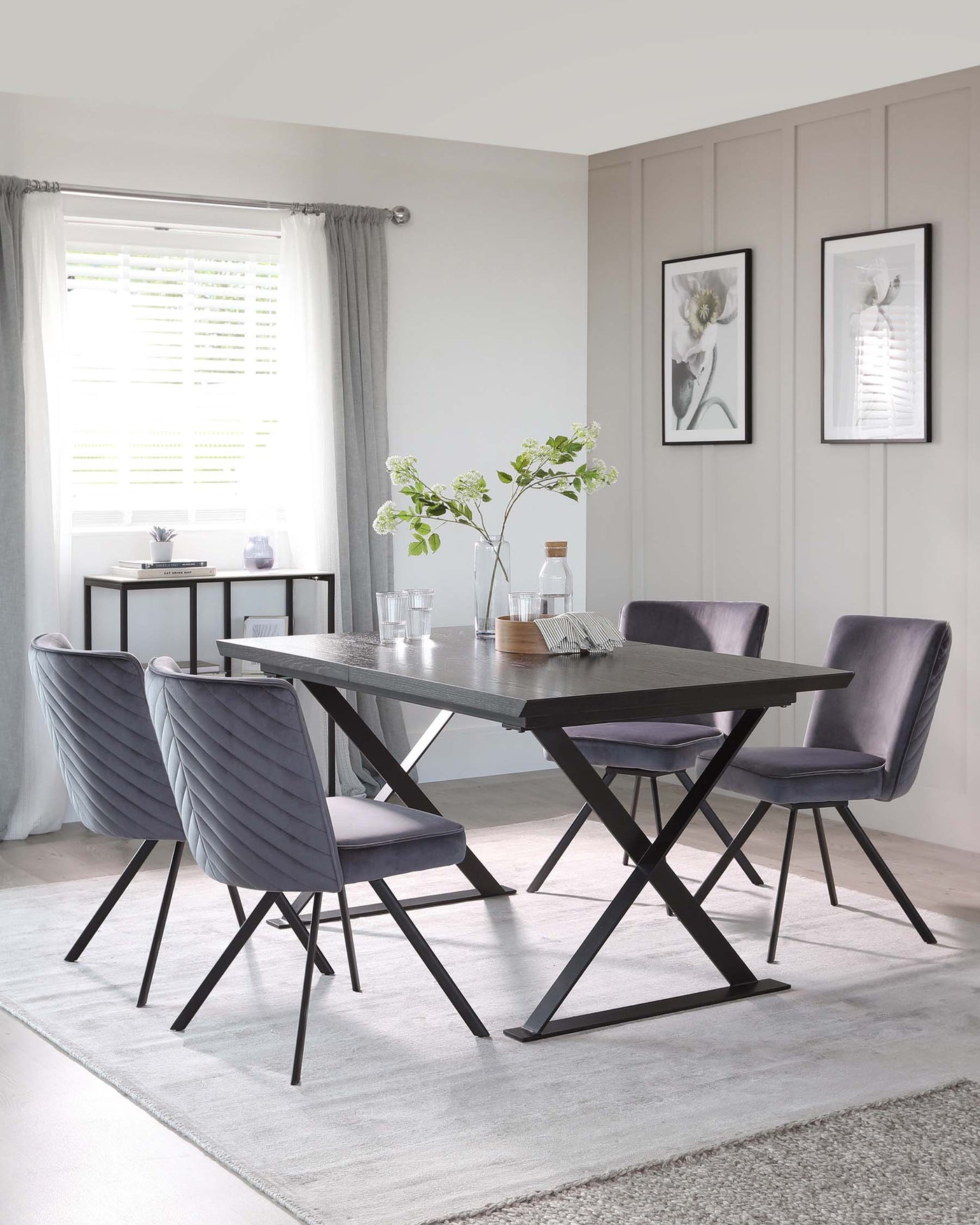 Modern dining room set featuring a rectangular dark wood table with an X-shaped leg design, accompanied by four upholstered dining chairs with channel tufting and sleek black legs. A minimalist sideboard with a two-tone finish completes the scene.