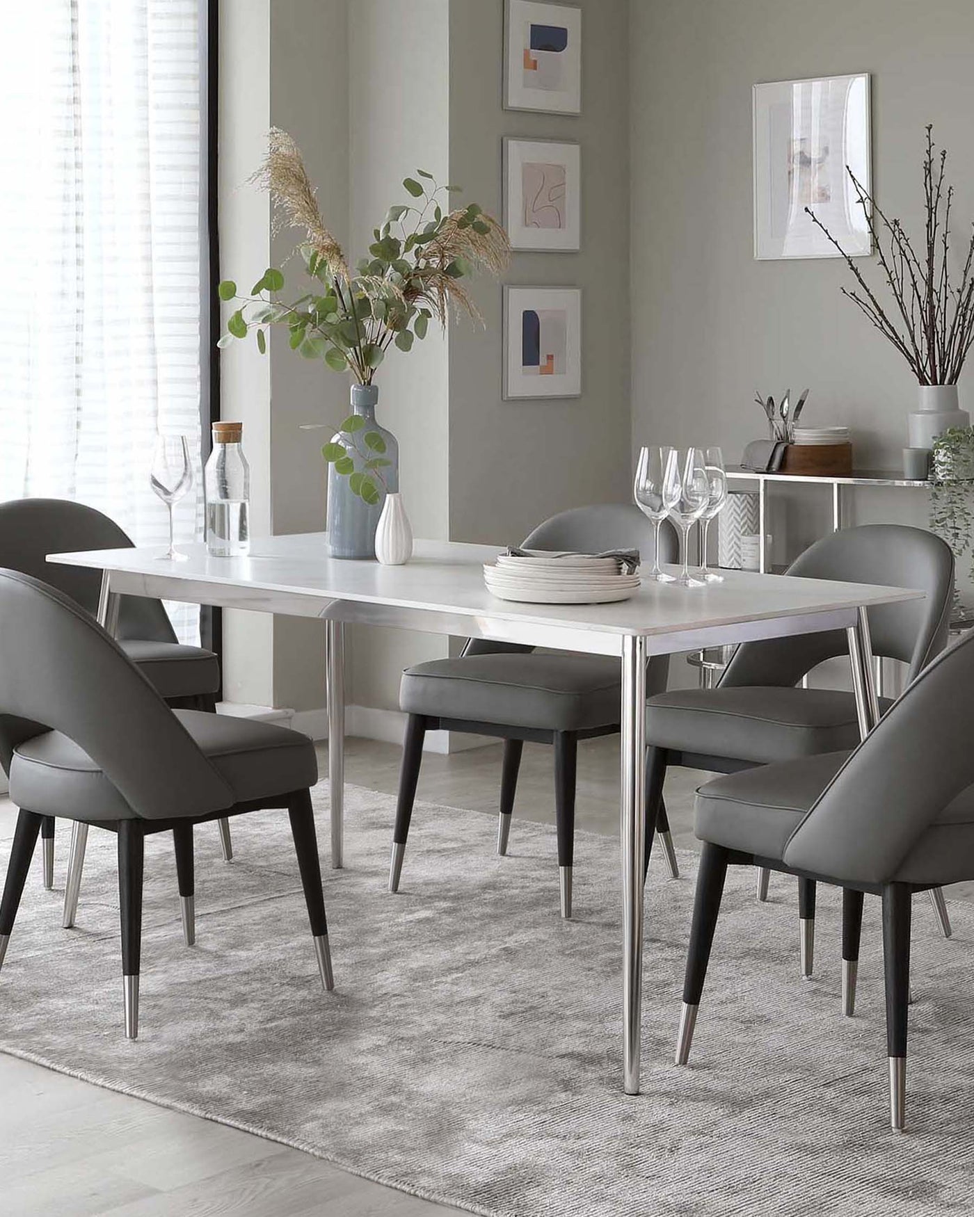 Modern dining room furniture set featuring a white rectangular table with a sleek, minimalist design and tapered metal legs. Accompanied by six elegant, dark grey upholstered chairs with comfortable curved backrests and slender metal legs, matching the table. Set on a textured grey area rug, creating a contemporary and inviting dining space.