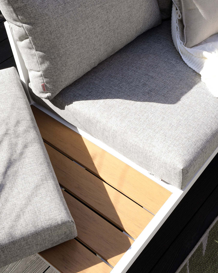 Modern outdoor corner sofa with light grey cushions, constructed with a wooden slatted base and white framework.