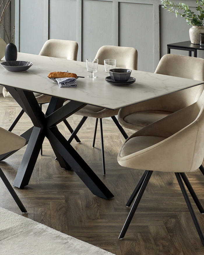 A modern dining table with a marble top and dark, cross-legged base, surrounded by beige, rounded dining chairs.