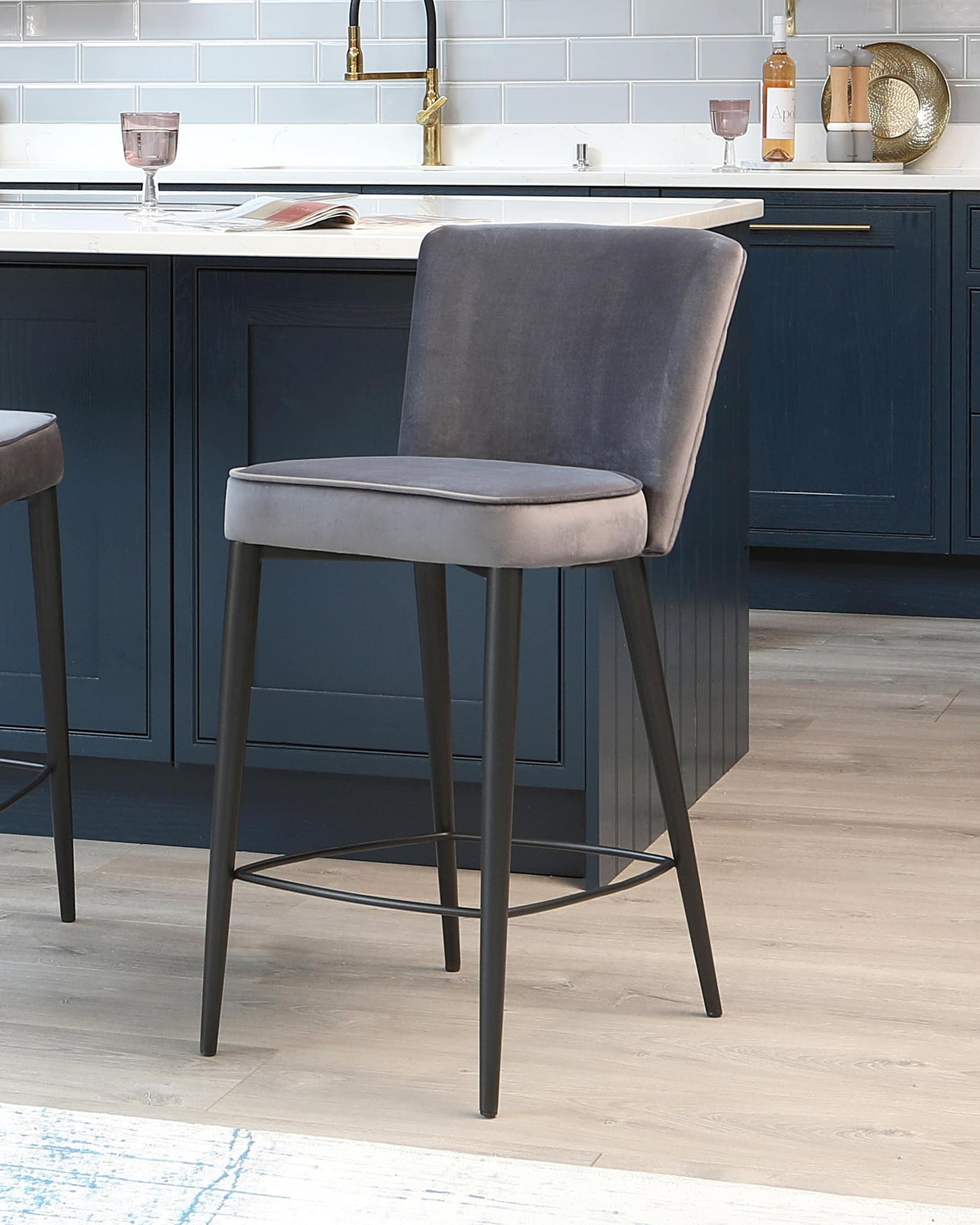 Elegant modern bar stool with a matte grey upholstered seat and backrest mounted on a slender black metal frame with four legs and a practical footrest.