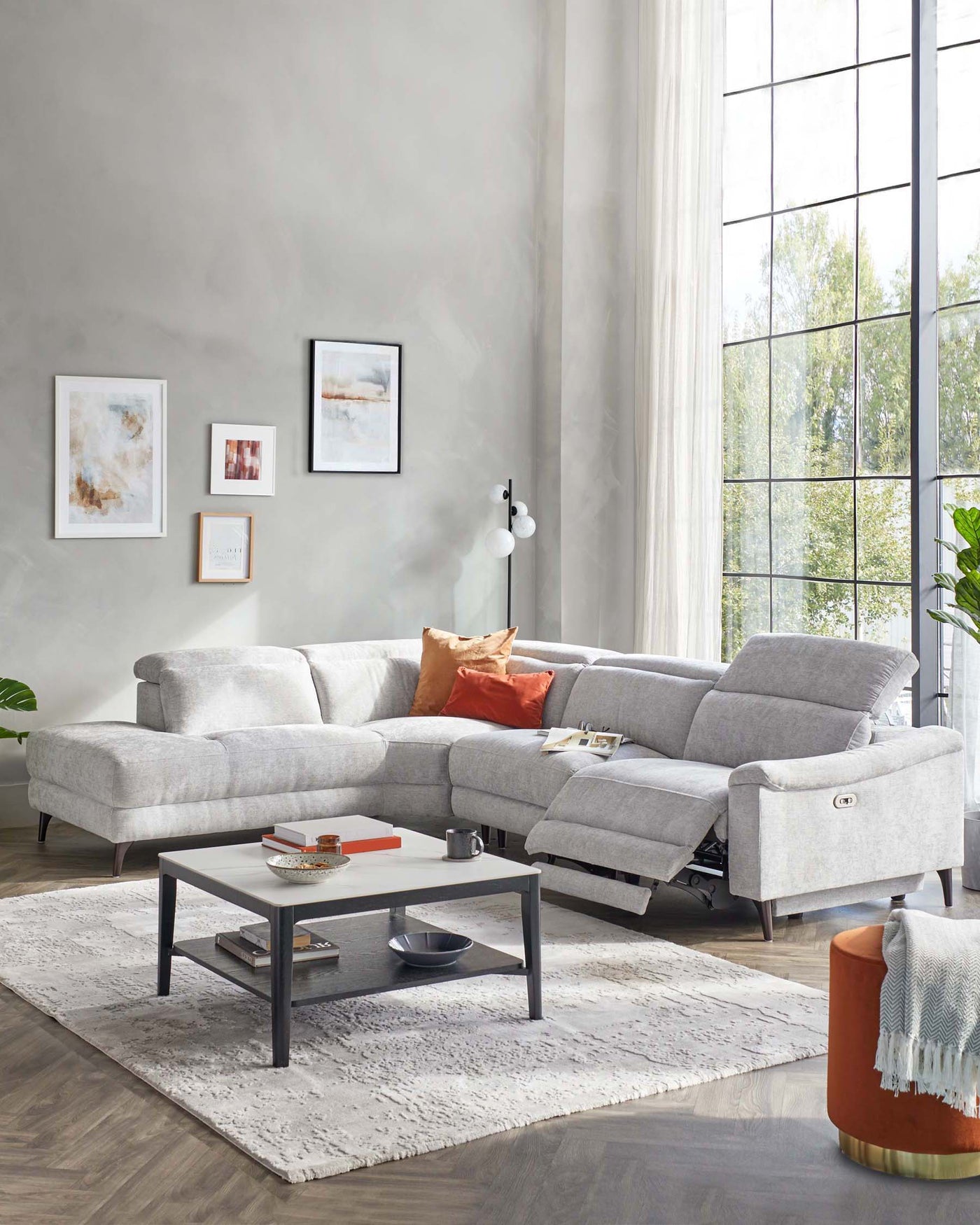 Contemporary light grey sectional sofa with various cushions, a rectangular black metal coffee table with a wooden top and a bottom shelf, situated on a plush grey area rug.