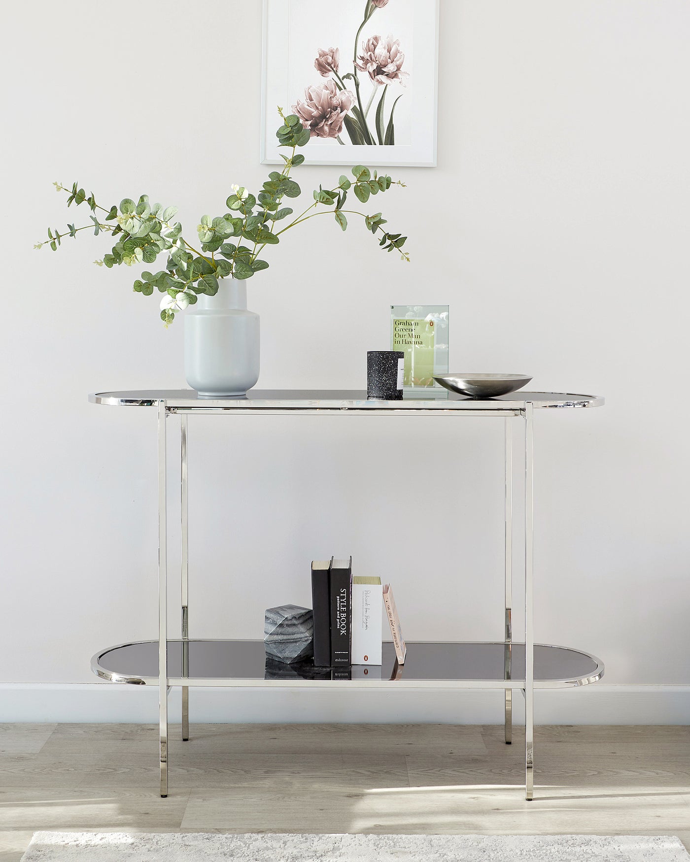 Modern minimalist console table with a sleek chrome metal frame and a rectangular clear glass top, featuring a second glass shelf for additional display and storage space.