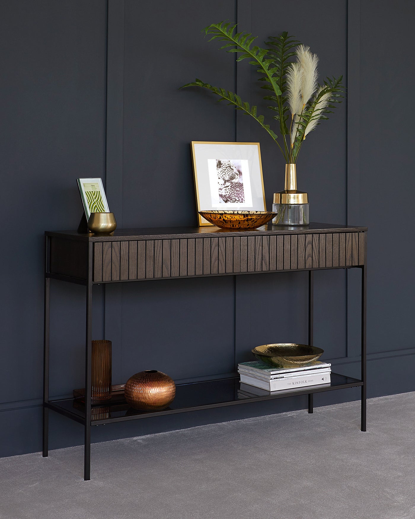 Slim, modern console table with dark wood finish and textured front, featuring two tiers with a lower metal shelf. The design includes straight, minimalist lines and a simple, elegant frame.