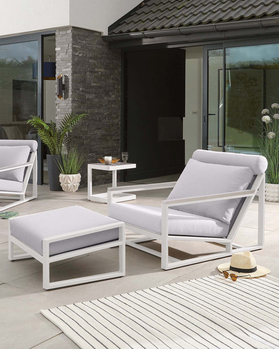 Modern outdoor furniture set featuring two white aluminium frame armchairs with light grey cushions, a matching white aluminium ottoman with a grey cushion, and a simple white side table, displayed on a patio area with a striped rug.