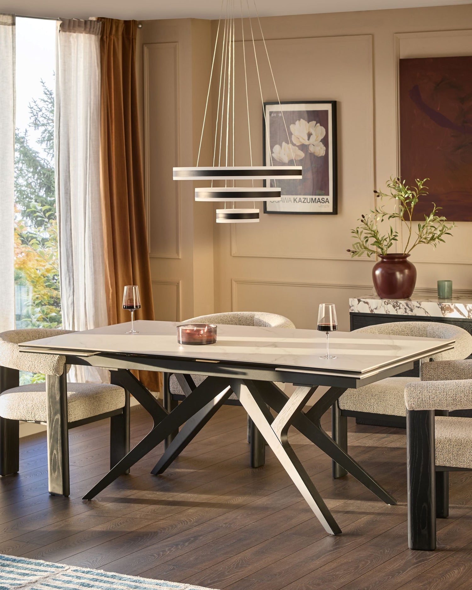 Jennet extending dining table in white ceramic and black wood with X-frame base, shown extended in modern dining room setting.