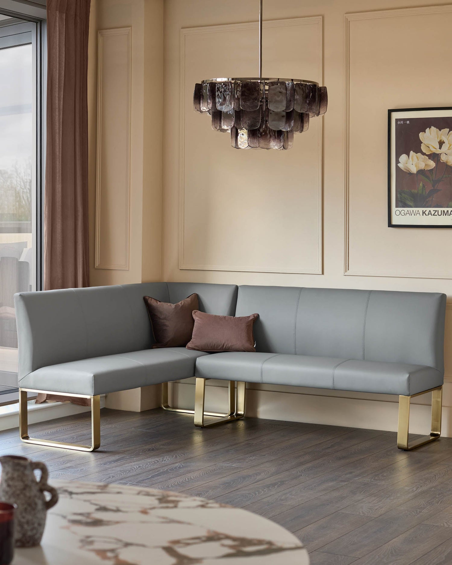 Loop 5-seater corner dining bench in mid-grey faux leather with brushed brass legs, shown in a modern living room setting.