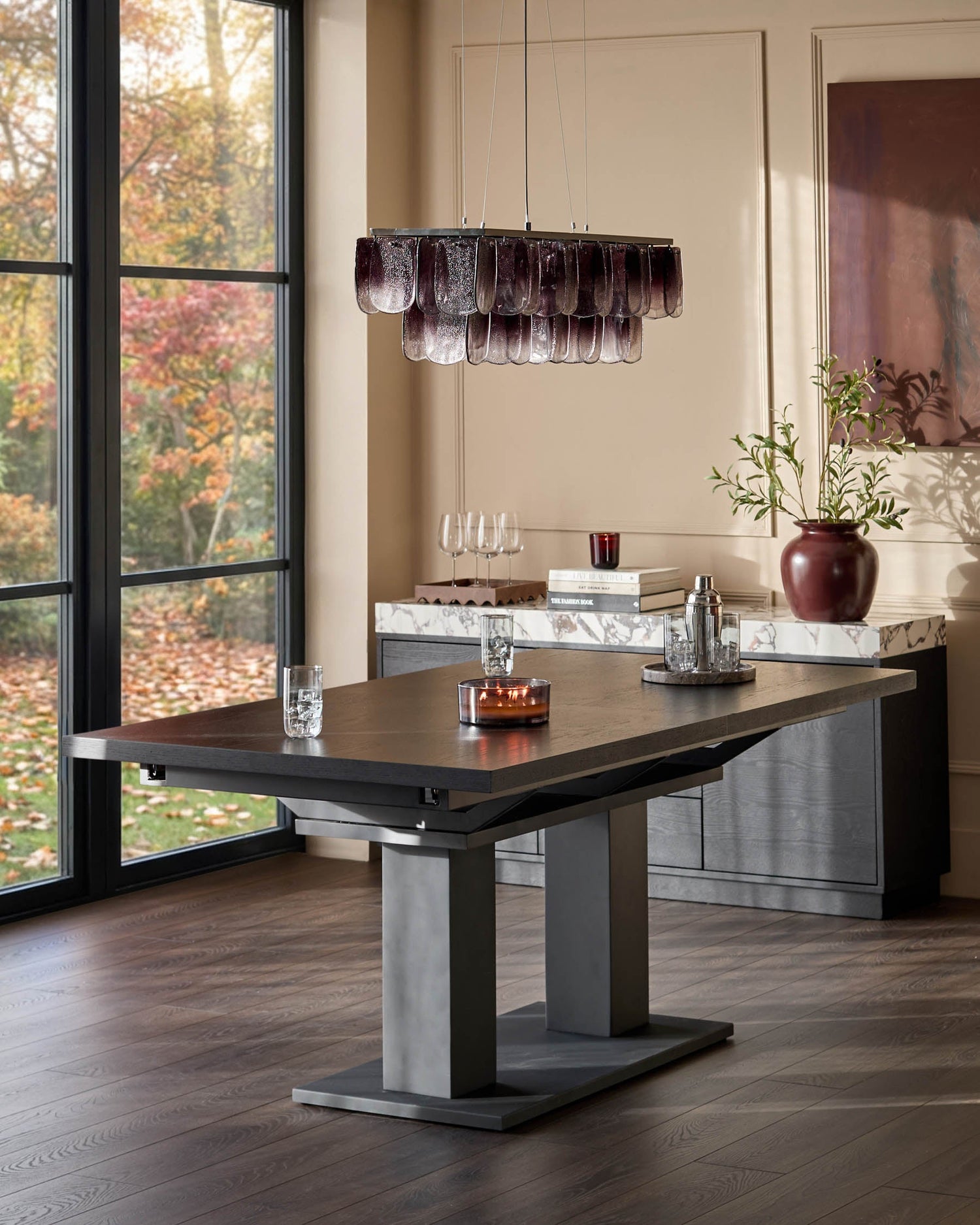 Morgan 8-10 seater dining table in dark wood with extending top and geometric base, shown in modern dining room setting.