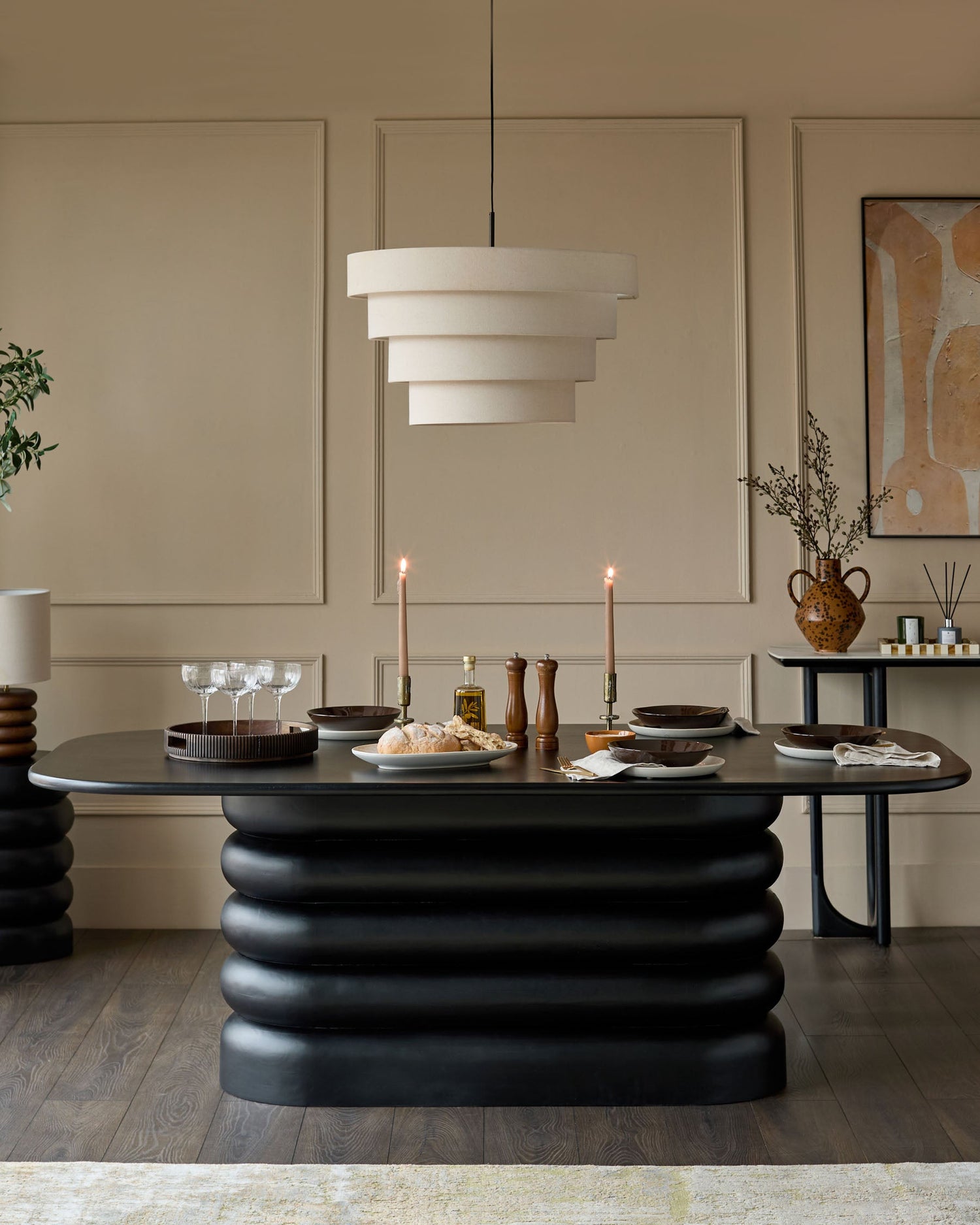Hepworth 8-seater dining table in black with sculptural ribbed base and rounded oval top, styled in a modern dining room.
