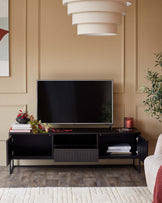 A black TV stand with shelving and storage, topped with a TV, decor and books.