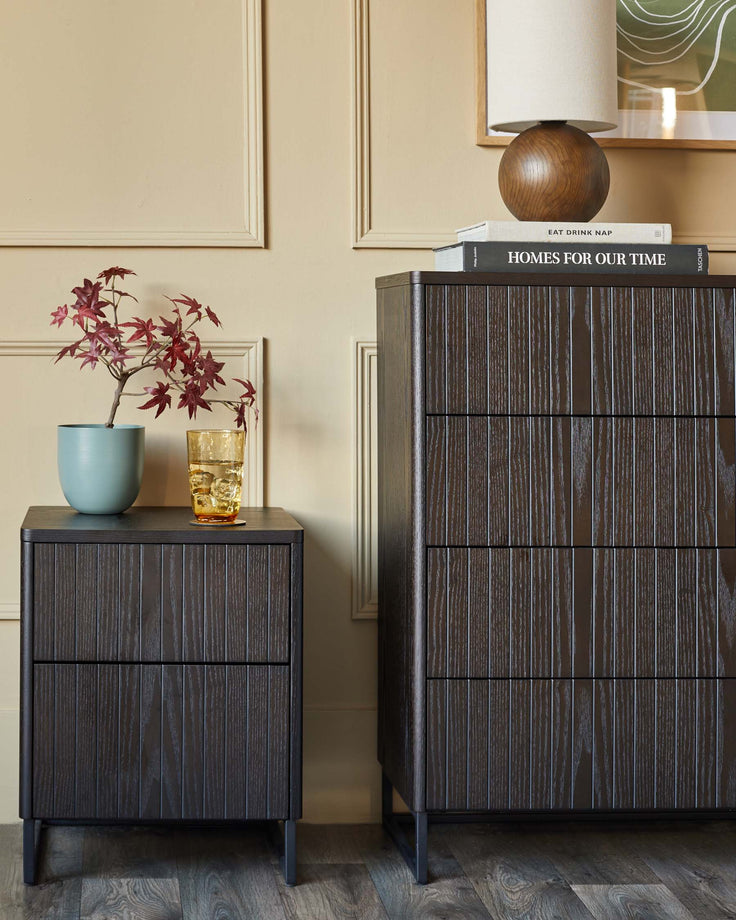 Dark wood bedside table & chest of drawers with a vertically ribbed design, on slim black legs.