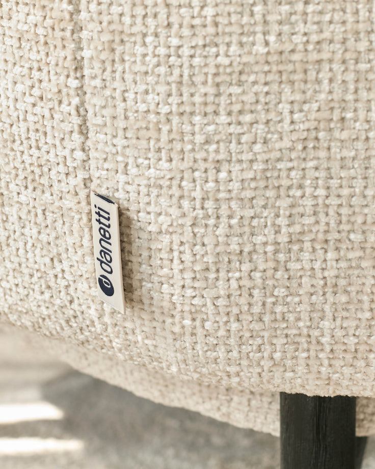Close-up of a textured, neutral-toned armchair with a discreet 'Danetti' label, highlighting its quality craftsmanship.