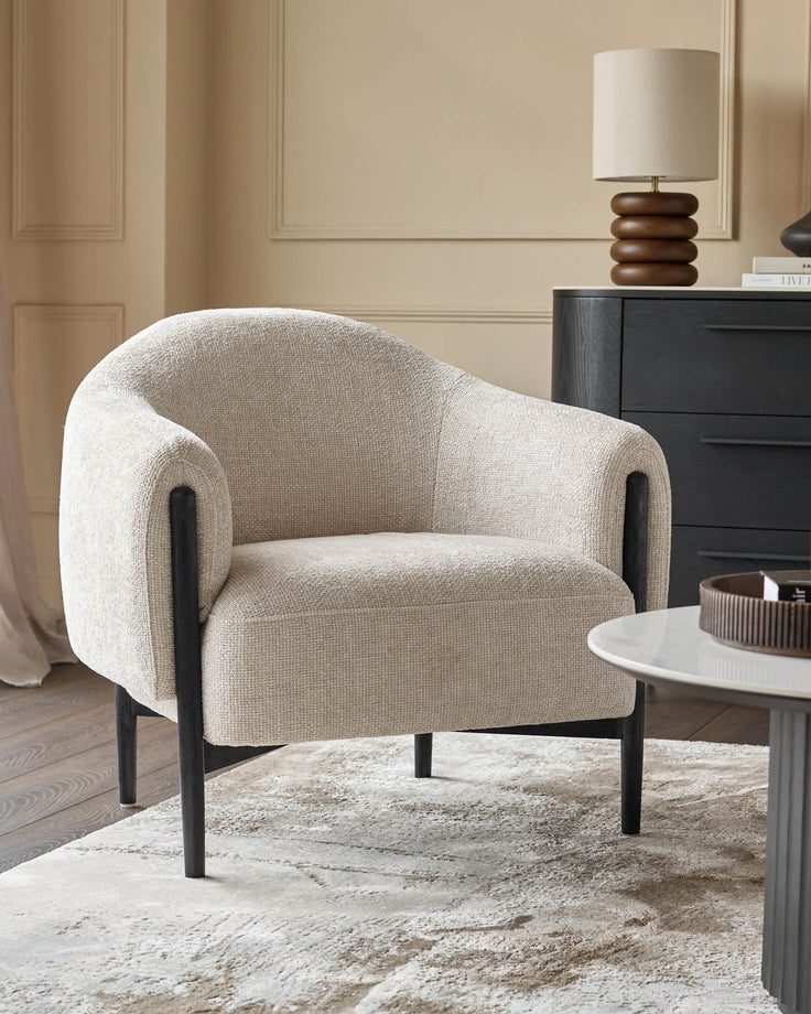 A stylish neutral armchair sits atop a patterned rug. A lamp and cabinet are in the background.