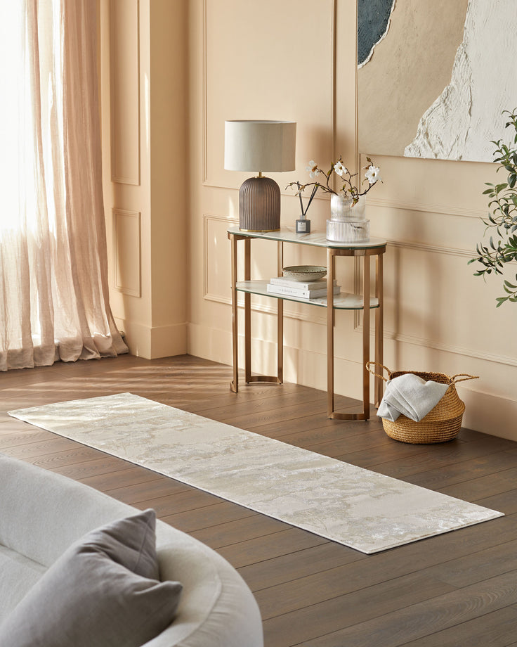 A modern interior featuring a sofa, stylish console table with lamp, and a textured rug on a wooden floor.