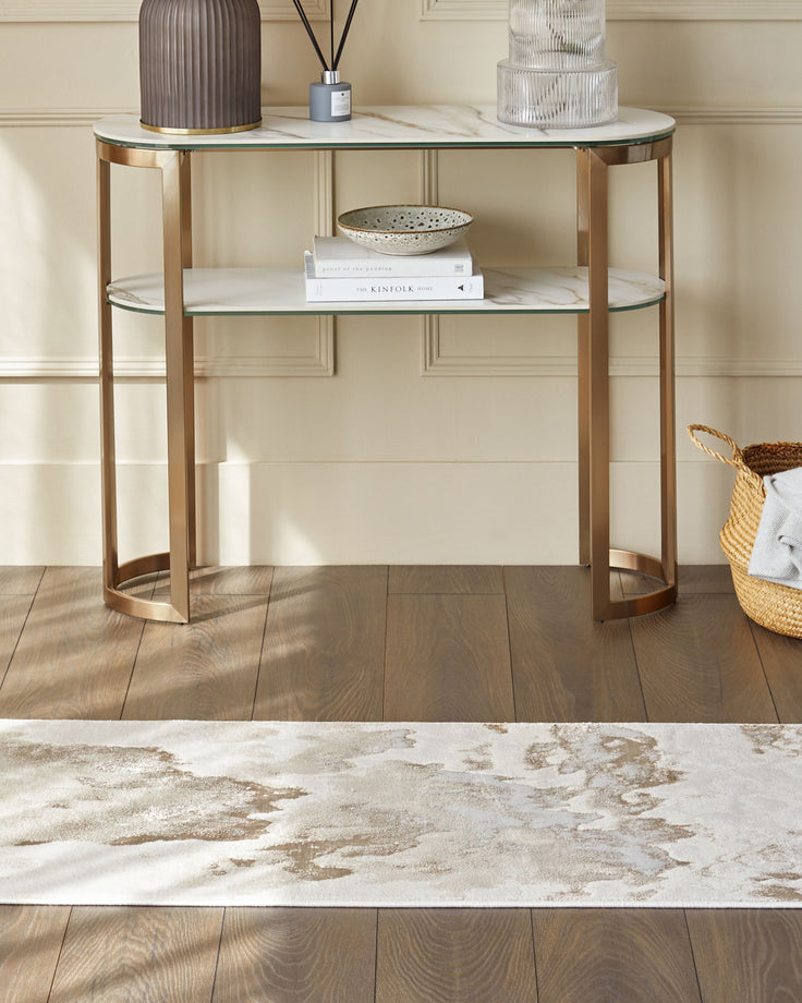 A two-tiered console table with a marble effect top, with decorative items. A basket sits to the right of the table.