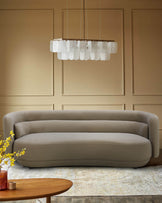 Stylish neutral-toned sofa under a unique chandelier, paired with a wooden coffee table and floral arrangement.