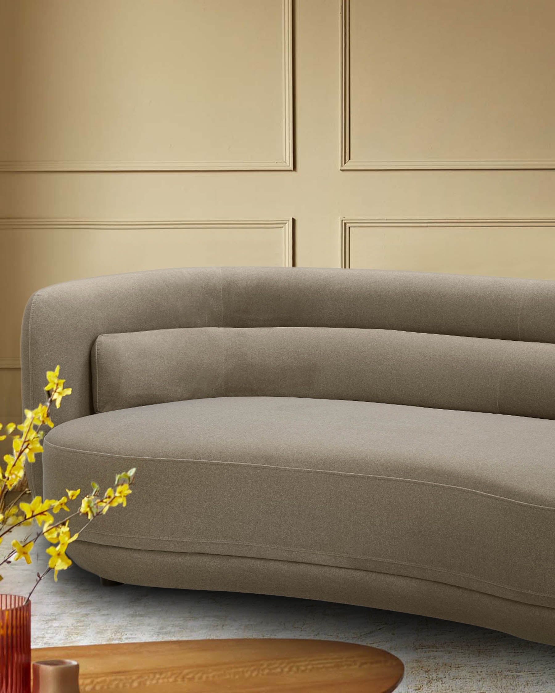 A curved, modern sofa in a neutral colour, with a minimalist design and sleek lines. Perfect for a stylish living room.