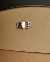 Close-up of polished chrome handle on natural wood frame of black-trimmed leaner mirror.