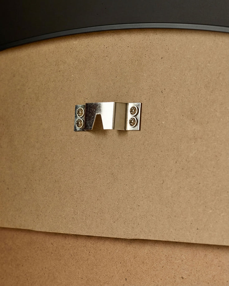 Close-up of polished chrome handle on natural wood frame of black-trimmed leaner mirror.
