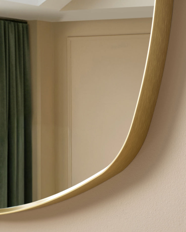 Channing Pebble Wall Mirror in Gold - curved gold frame with integrated LED lighting, installed in modern beige interior.