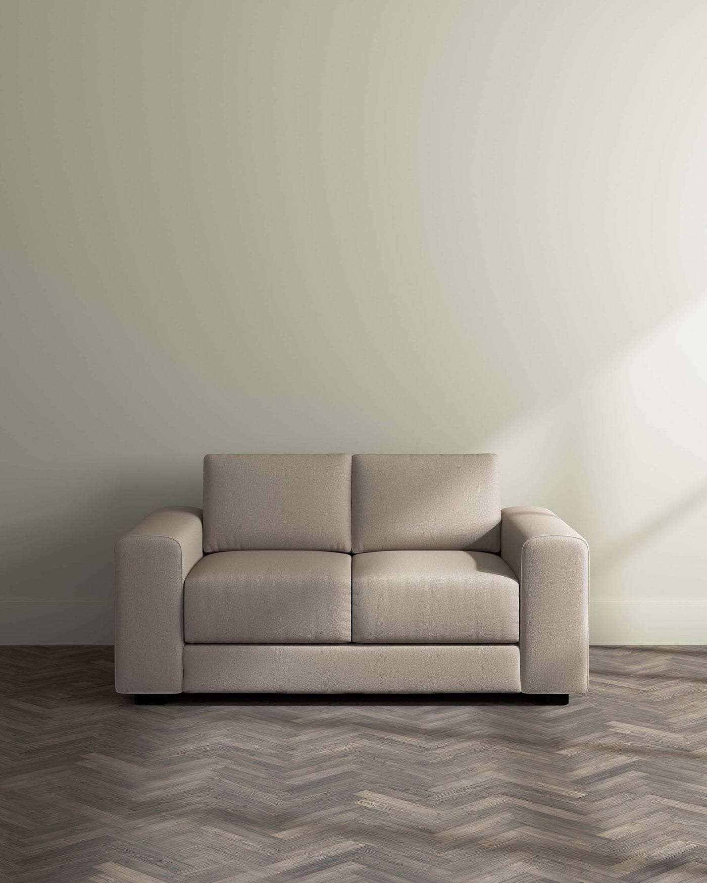 Modern beige three-seater sofa with sleek design and rounded armrests on a herringbone patterned floor against a light grey wall.