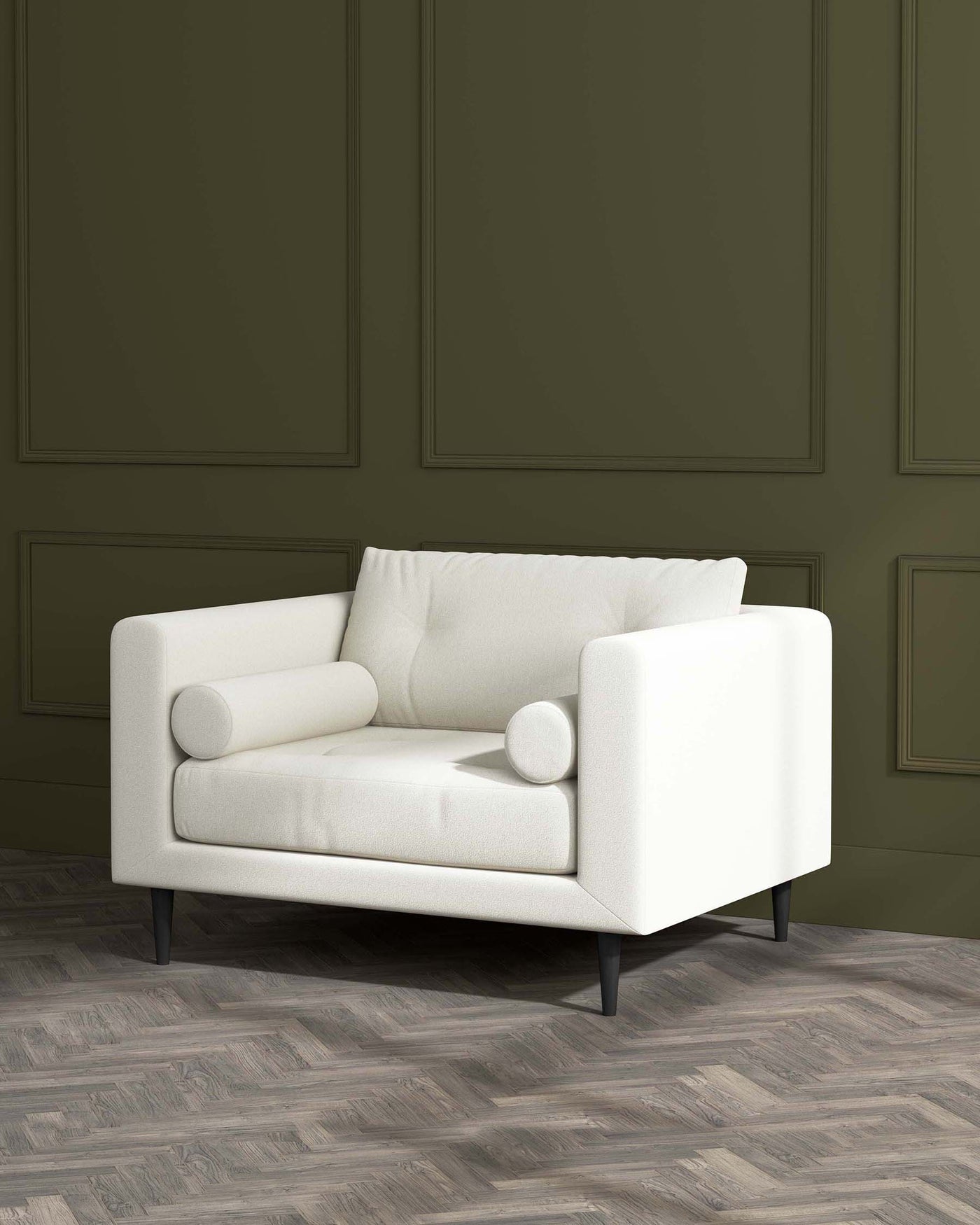 A modern white armchair with clean lines, featuring plush cushions and cylindrical armrests on minimalist black wooden legs, set against a green panelled wall and herringbone parquet flooring.
